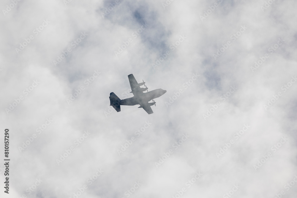 Four-engine turboprop military transport aircraft climbing through clouds Four-engine turboprop military transport aircraft climbing through clouds