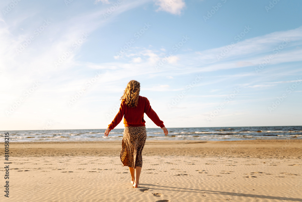 Beautiful woman walks along a picturesque sandy beach at sunset. Travel, weekend, relax and lifestyle concept. Beautiful woman walks along a picturesque sandy beach at sunset. Travel, weekend, relax and lifestyle concept.