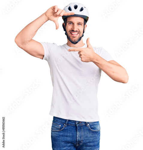 Young handsome man wearing bike helmet smiling making frame with hands and fingers with happy face. creativity and photography concept.