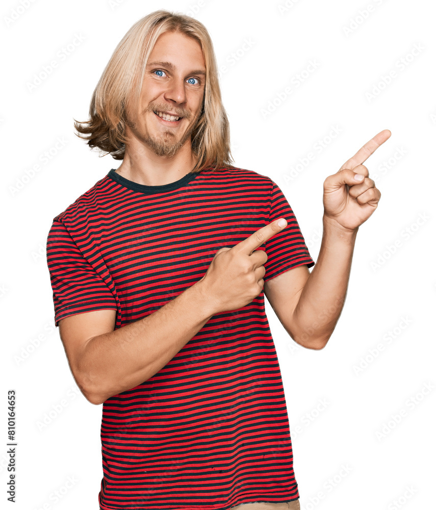 Caucasian man with blond long hair wearing casual striped t shirt smiling and looking at the camera pointing with two hands and fingers to the side. Caucasian man with blond long hair wearing casual striped t shirt smiling and looking at the camera pointing with two hands and fingers to the side.
