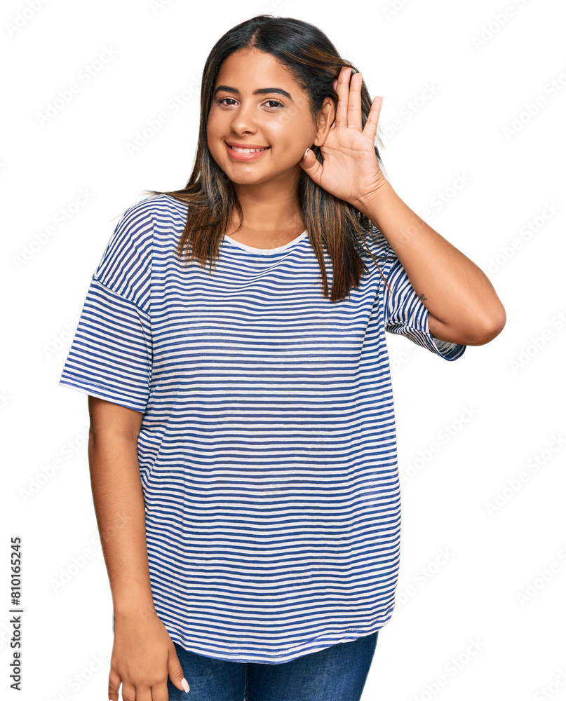 Young latin girl wearing casual clothes smiling with hand over ear listening an hearing to rumor or gossip. deafness concept. Young latin girl wearing casual clothes smiling with hand over ear listening an hearing to rumor or gossip. deafness concept.