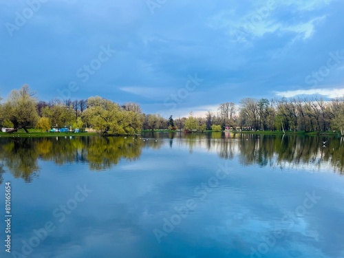 Pond in the park, evening time, trees reflection on the water surface