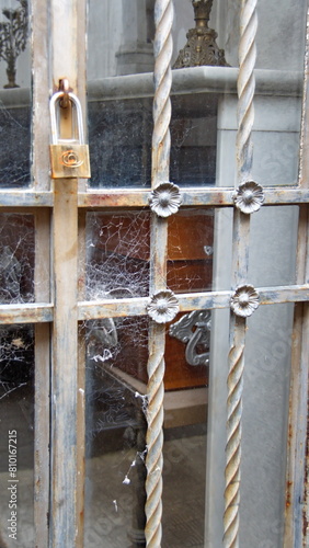 Cobwebs on the metal grate over a glass door to a mausoleum in La Recoleta Cemetery in Buenos Aires, Argentina