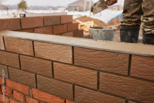 professional construction worker laying bricks and building barbecue in industrial site. Detail of hand adjusting bricks
