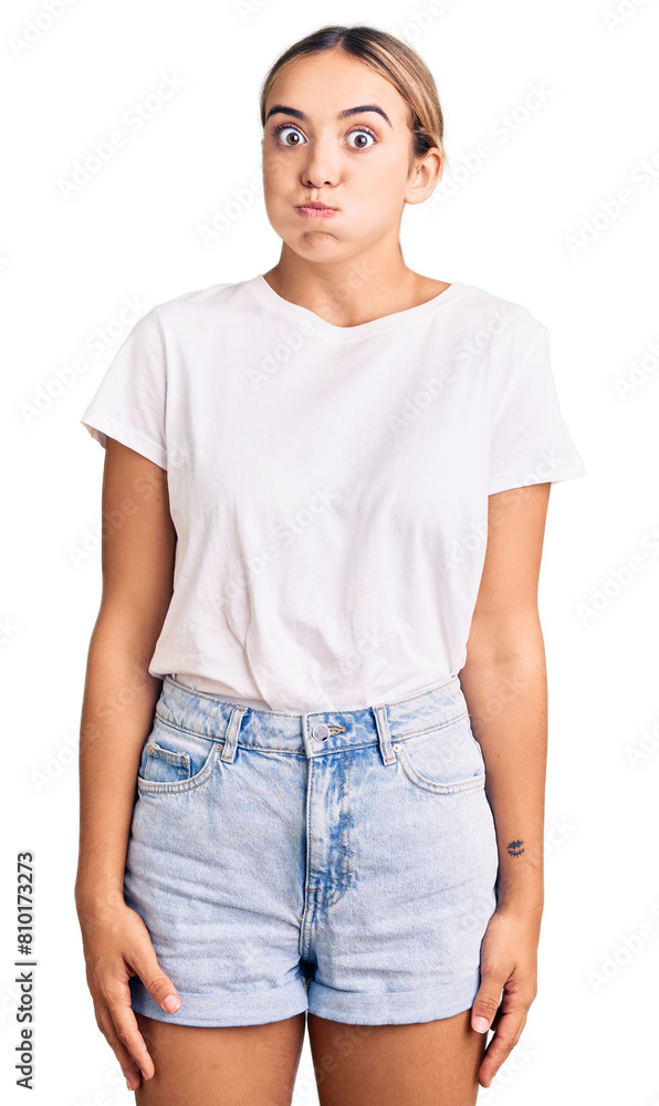 Young beautiful blonde woman wearing casual white tshirt puffing cheeks with funny face. mouth inflated with air, crazy expression. Young beautiful blonde woman wearing casual white tshirt puffing cheeks with funny face. mouth inflated with air, crazy expression.