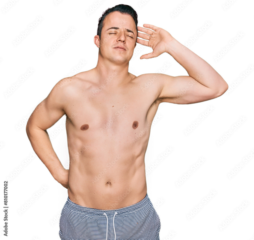 Fototapeta premium Handsome young man wearing swimwear shirtless stretching back, tired and relaxed, sleepy and yawning for early morning