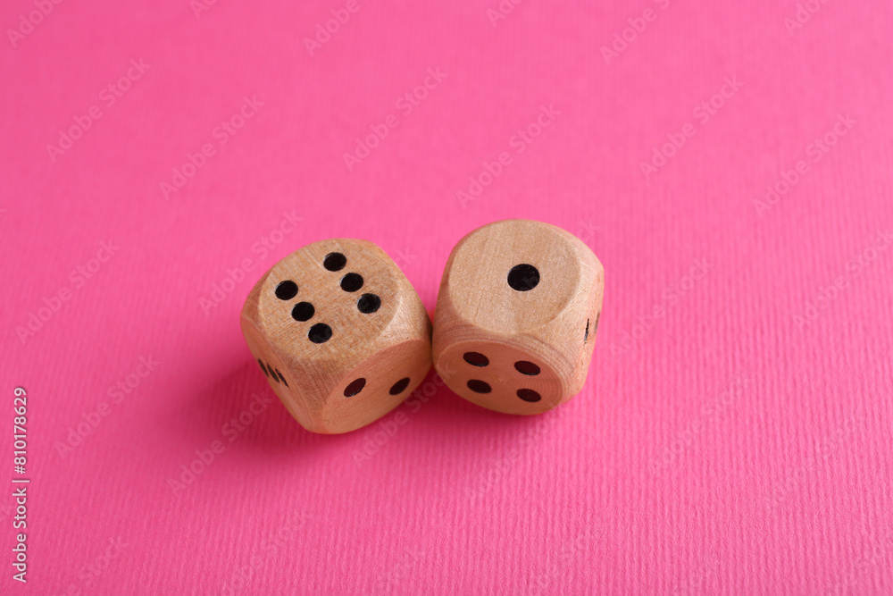 Two wooden game dices on pink background, closeup