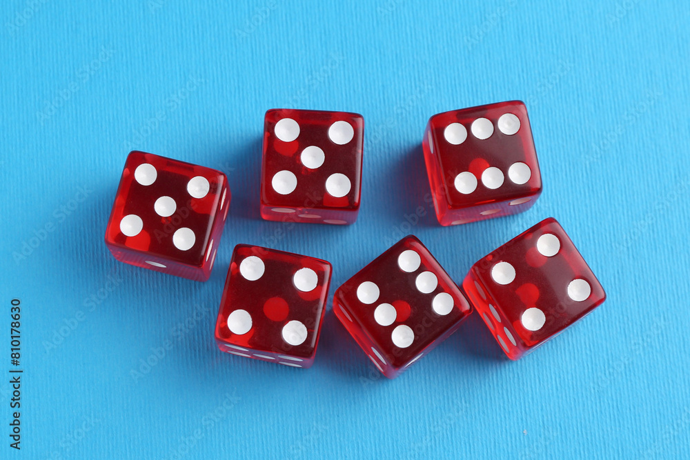 Many red game dices on light blue background, flat lay Many red game dices on light blue background, flat lay
