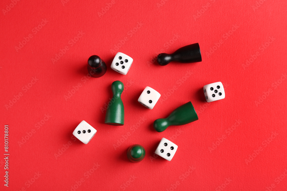 Many white dices and color game pieces on red background, flat lay