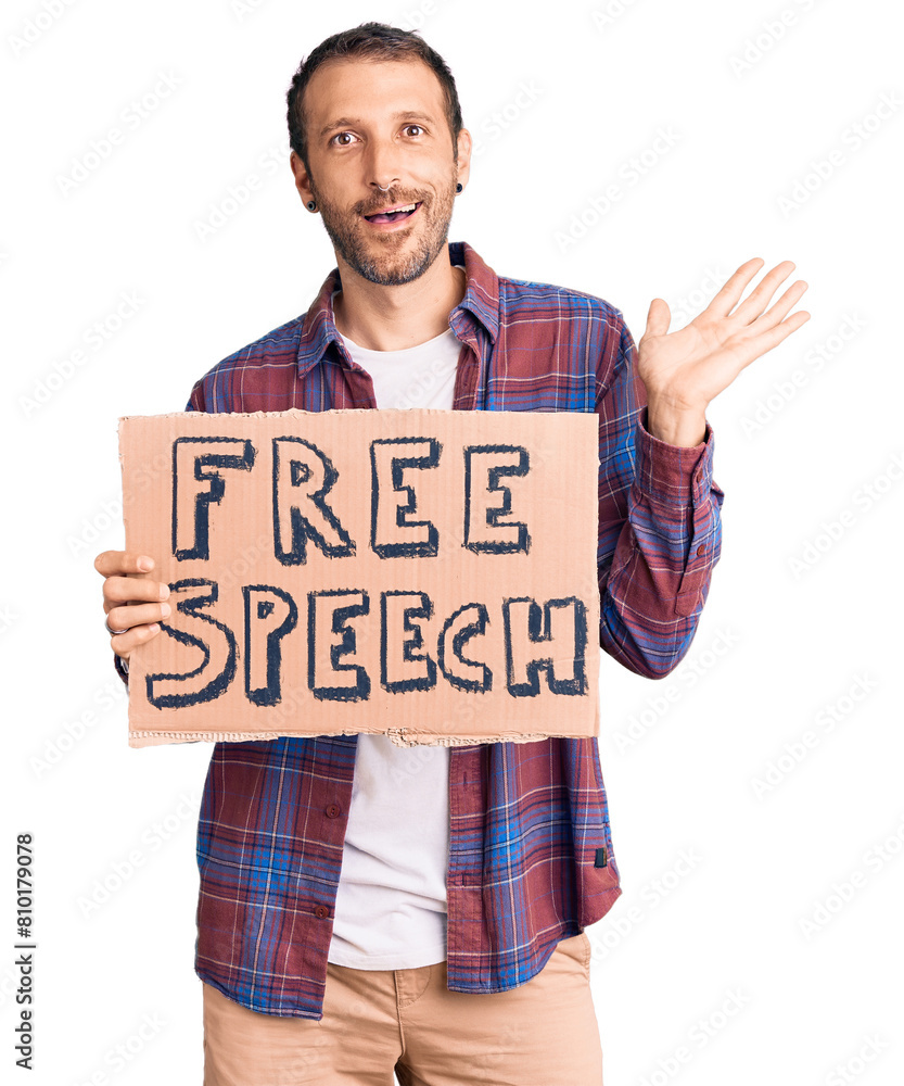 Young handsome man holding free speech banner celebrating victory with happy smile and winner expression with raised hands Young handsome man holding free speech banner celebrating victory with happy smile and winner expression with raised hands