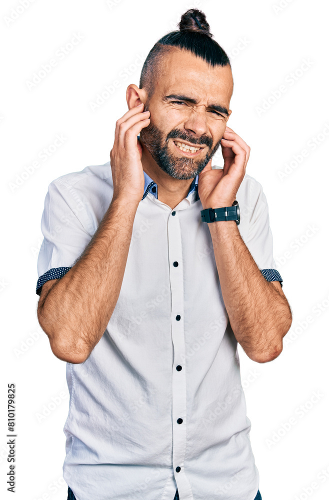 Hispanic man with ponytail wearing casual white shirt covering ears with fingers with annoyed expression for the noise of loud music. deaf concept. Hispanic man with ponytail wearing casual white shirt covering ears with fingers with annoyed expression for the noise of loud music. deaf concept.