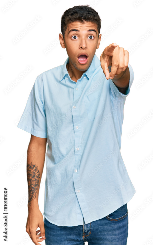 Young handsome african american man wearing casual clothes pointing with finger surprised ahead, open mouth amazed expression, something on the front Young handsome african american man wearing casual clothes pointing with finger surprised ahead, open mouth amazed expression, something on the front