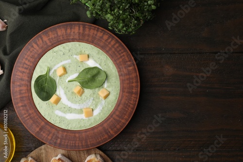 Delicious spinach cream soup with leaves and cheese in bowl on wooden table, flat lay. Space for text