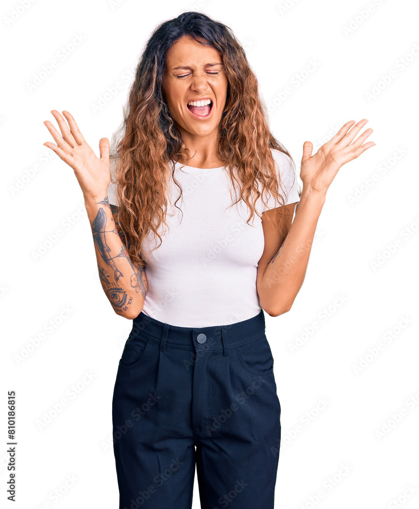 Young hispanic woman with tattoo wearing casual white tshirt celebrating mad and crazy for success with arms raised and closed eyes screaming excited. winner concept Young hispanic woman with tattoo wearing casual white tshirt celebrating mad and crazy for success with arms raised and closed eyes screaming excited. winner concept