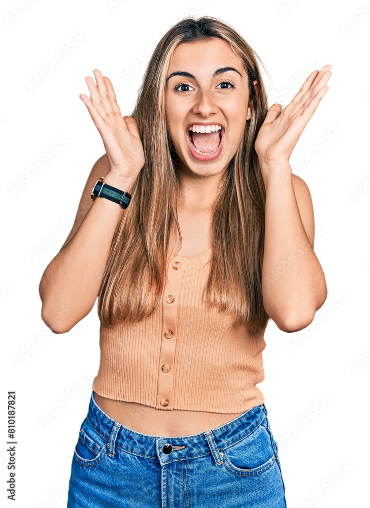 Hispanic young woman wearing casual summer shirt celebrating crazy and amazed for success with arms raised and open eyes screaming excited. winner concept Hispanic young woman wearing casual summer shirt celebrating crazy and amazed for success with arms raised and open eyes screaming excited. winner concept
