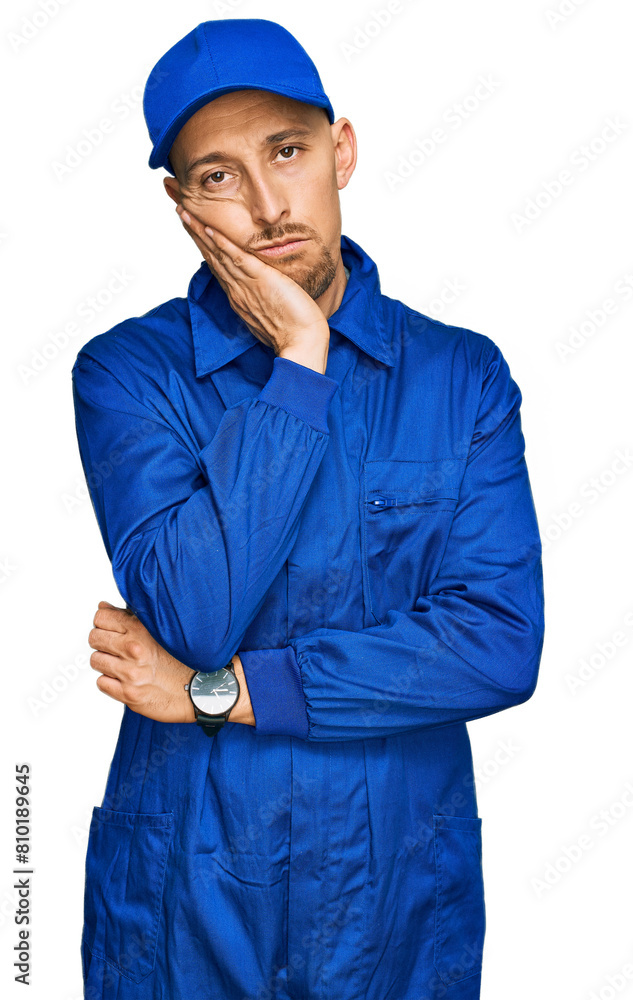 Bald man with beard wearing builder jumpsuit uniform thinking looking tired and bored with depression problems with crossed arms. Bald man with beard wearing builder jumpsuit uniform thinking looking tired and bored with depression problems with crossed arms.