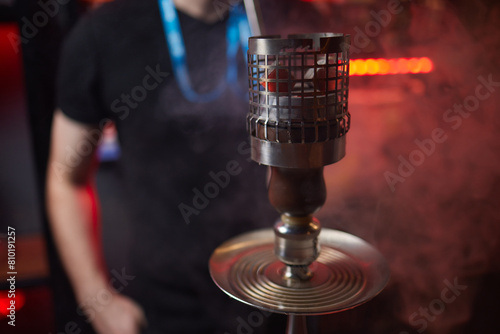 Close up of a hookah made of metal and glass on a wooden table