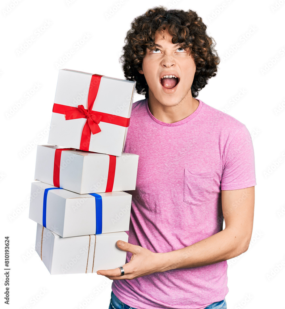 Caucasian teenager holding gifts angry and mad screaming frustrated and furious, shouting with anger looking up. Caucasian teenager holding gifts angry and mad screaming frustrated and furious, shouting with anger looking up.