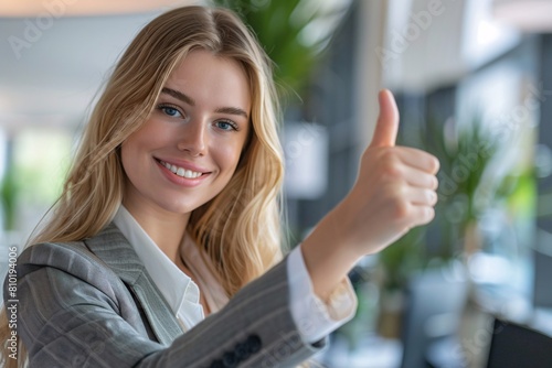 A confident businesswoman giving a thumbs up in the office © Maelgoa