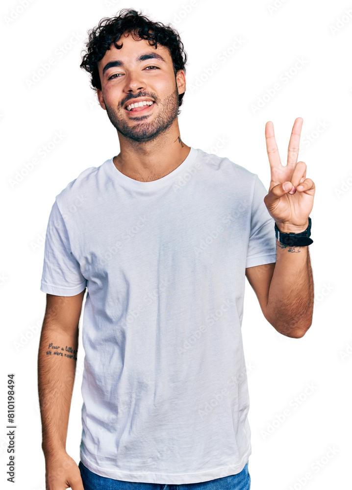 Hispanic young man with beard wearing casual white t shirt smiling looking to the camera showing fingers doing victory sign. number two. Hispanic young man with beard wearing casual white t shirt smiling looking to the camera showing fingers doing victory sign. number two.