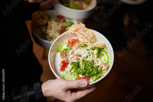 Men s waiter hands hold a Caesar salad