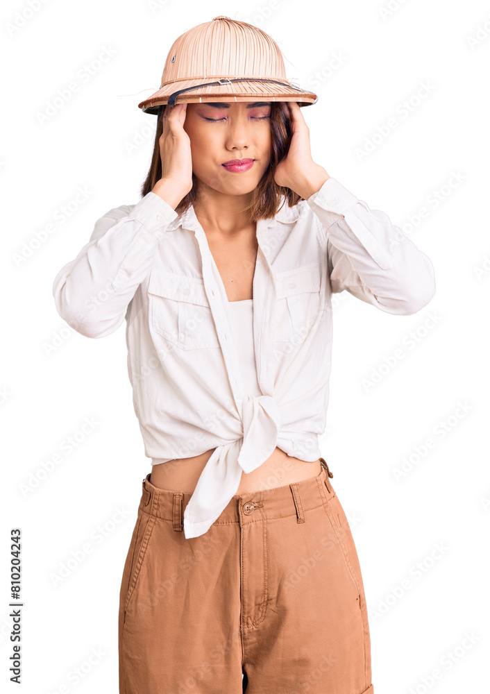 Young beautiful chinese girl wearing explorer hat suffering from headache desperate and stressed because pain and migraine. hands on head. Young beautiful chinese girl wearing explorer hat suffering from headache desperate and stressed because pain and migraine. hands on head.