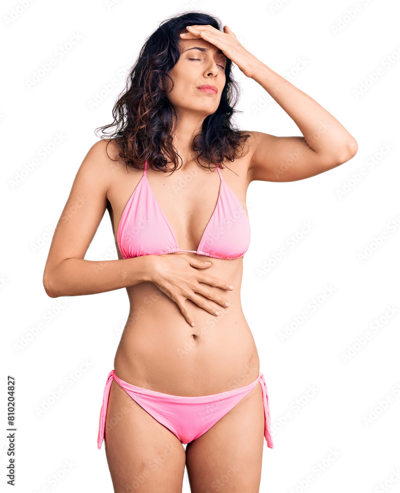 Obraz premium Young beautiful hispanic woman wearing bikini touching forehead for illness and fever, flu and cold, virus sick