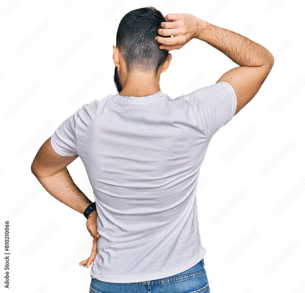 Young man with beard wearing casual white t shirt backwards thinking about doubt with hand on head Young man with beard wearing casual white t shirt backwards thinking about doubt with hand on head