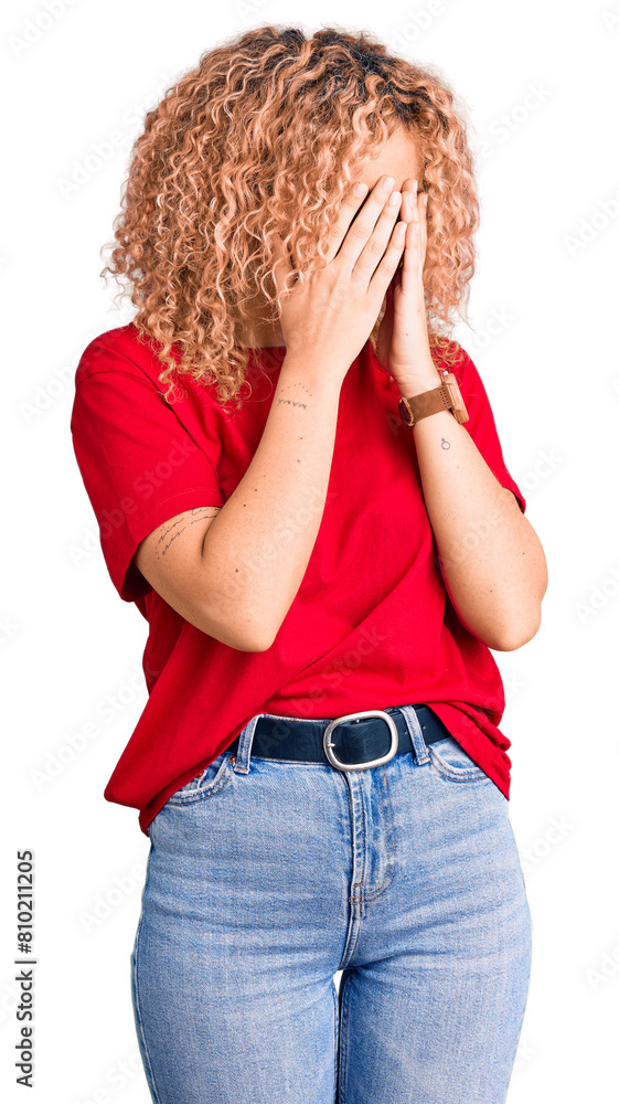 Young blonde woman with curly hair wearing casual red tshirt with sad expression covering face with hands while crying. depression concept. Young blonde woman with curly hair wearing casual red tshirt with sad expression covering face with hands while crying. depression concept.