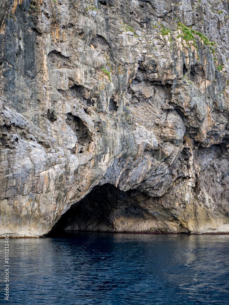 Entrance of Cova de Ses Tres Maries sea cave within Mallorca rugged cliffs accessible solely by sea, a former smugglers hideout now beckoning adventurous kayaking trips, ideal for memorable vacations.