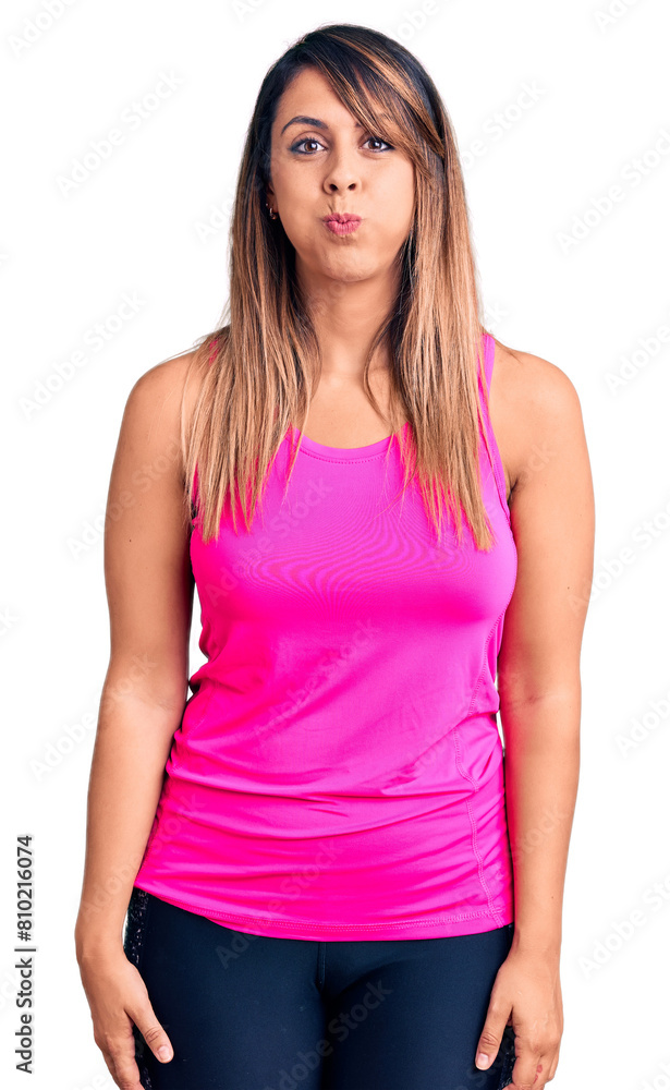 Young beautiful woman wearing sportswear puffing cheeks with funny face. mouth inflated with air, crazy expression. Young beautiful woman wearing sportswear puffing cheeks with funny face. mouth inflated with air, crazy expression.