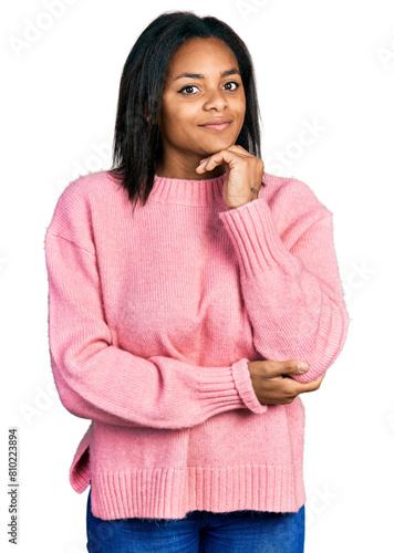 Beautiful hispanic woman wearing casual winter sweater with hand on chin thinking about question, pensive expression. smiling and thoughtful face. doubt concept.
