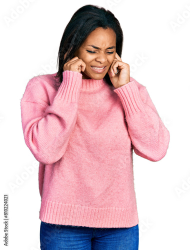 Beautiful hispanic woman wearing casual winter sweater covering ears with fingers with annoyed expression for the noise of loud music. deaf concept.