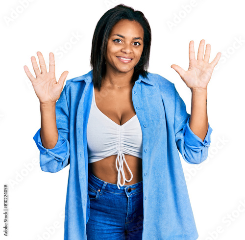 Beautiful hispanic woman wearing casual denim jacket showing and pointing up with fingers number ten while smiling confident and happy.