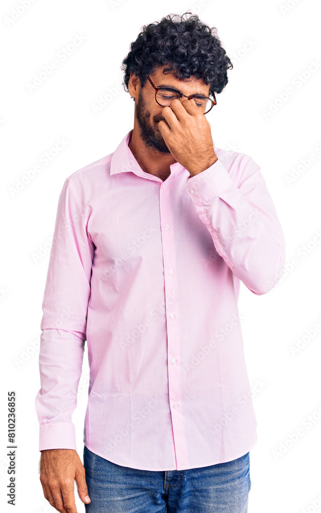 Handsome young man with curly hair and bear wearing business clothes tired rubbing nose and eyes feeling fatigue and headache. stress and frustration concept. Handsome young man with curly hair and bear wearing business clothes tired rubbing nose and eyes feeling fatigue and headache. stress and frustration concept.