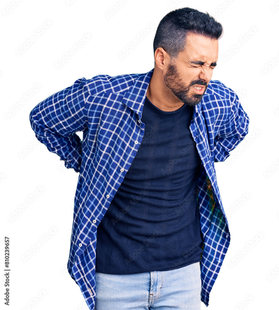 Young hispanic man wearing casual clothes suffering of backache, touching back with hand, muscular pain Young hispanic man wearing casual clothes suffering of backache, touching back with hand, muscular pain