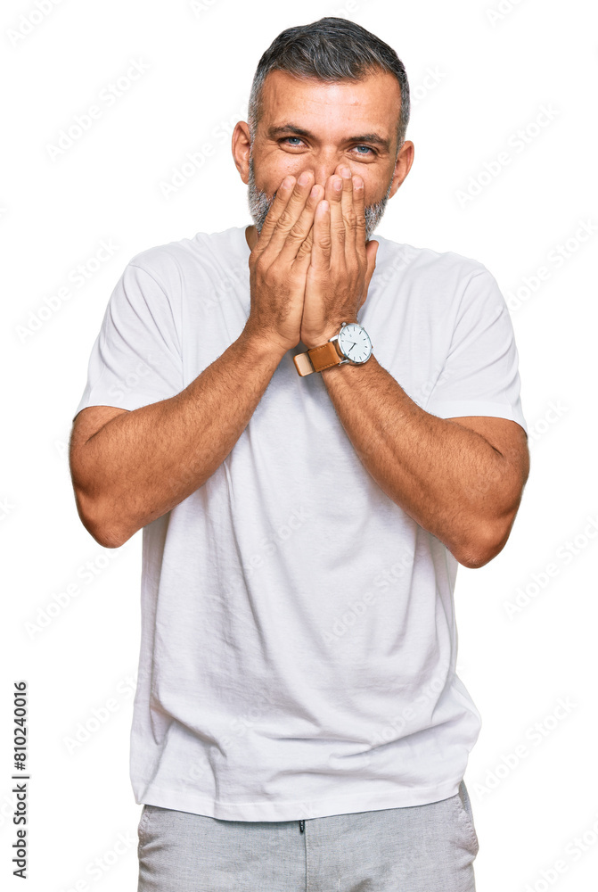 Middle age handsome man wearing casual white tshirt laughing and embarrassed giggle covering mouth with hands, gossip and scandal concept Middle age handsome man wearing casual white tshirt laughing and embarrassed giggle covering mouth with hands, gossip and scandal concept