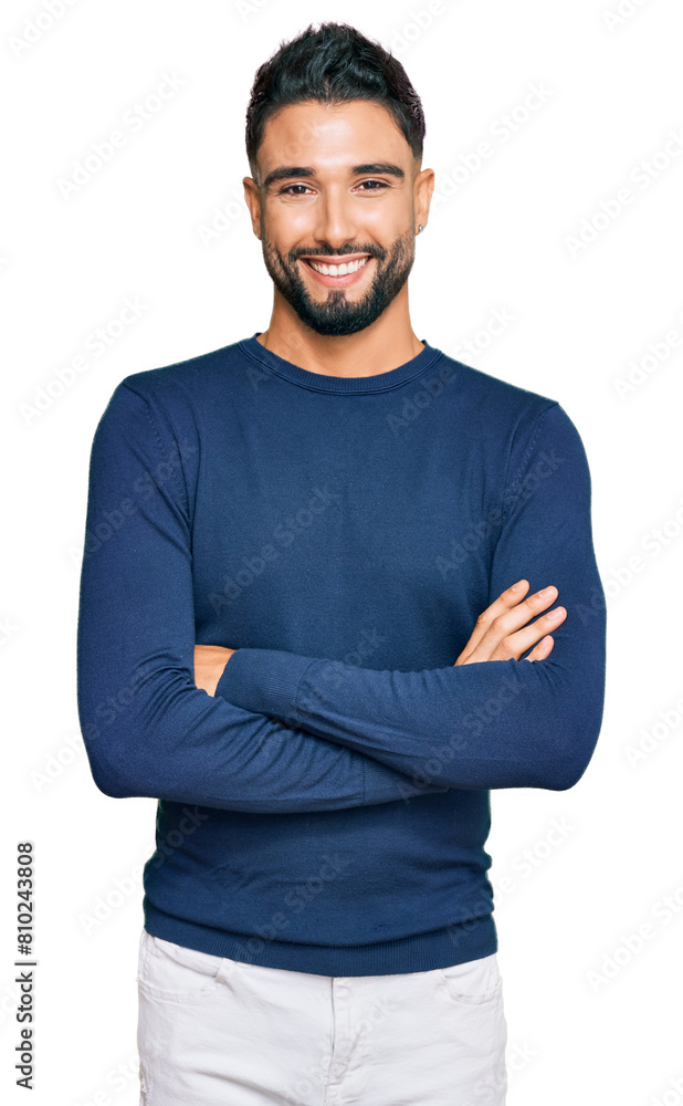 Young man with beard wearing casual blue winter sweater happy face smiling with crossed arms looking at the camera. positive person. Young man with beard wearing casual blue winter sweater happy face smiling with crossed arms looking at the camera. positive person.