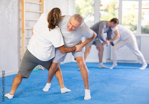 Man and senior male athletes practice Brazilian jiu Jitsu Aikido Wing chun wrestling. Training at Academy of Martial Arts martial arts hand-to-hand combat.