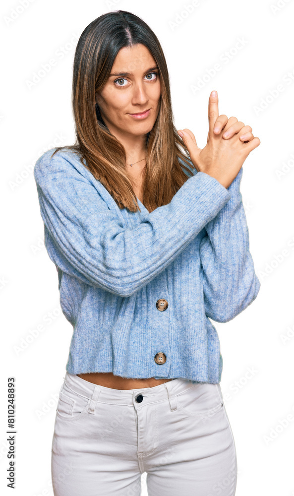 Young woman wearing casual clothes holding symbolic gun with hand gesture, playing killing shooting weapons, angry face Young woman wearing casual clothes holding symbolic gun with hand gesture, playing killing shooting weapons, angry face