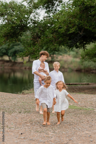 children, brothers and sisters walk near the lake in the summer, a large family