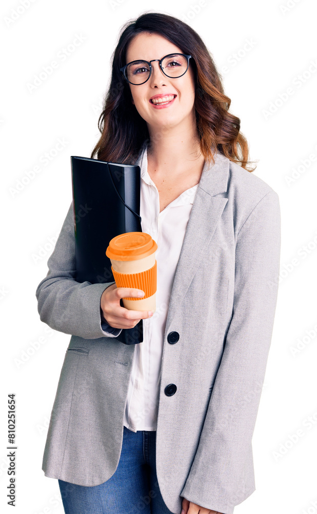 Beautiful young brunette woman holding business folder and drinking coffee looking positive and happy standing and smiling with a confident smile showing teeth Beautiful young brunette woman holding business folder and drinking coffee looking positive and happy standing and smiling with a confident smile showing teeth