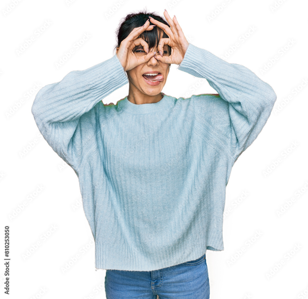 Young hispanic woman wearing casual clothes doing ok gesture like binoculars sticking tongue out, eyes looking through fingers. crazy expression. Young hispanic woman wearing casual clothes doing ok gesture like binoculars sticking tongue out, eyes looking through fingers. crazy expression.