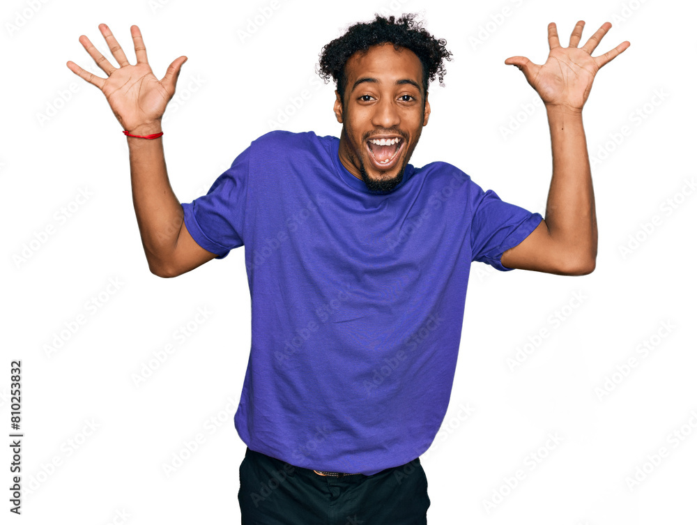Young african american man with beard wearing casual purple t shirt celebrating crazy and amazed for success with arms raised and open eyes screaming excited. winner concept Young african american man with beard wearing casual purple t shirt celebrating crazy and amazed for success with arms raised and open eyes screaming excited. winner concept
