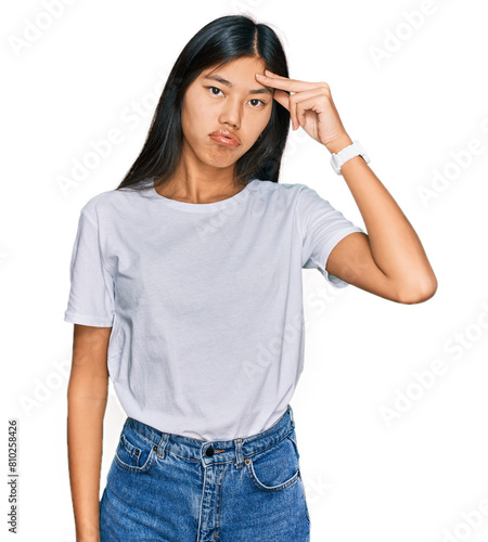 Beautiful young asian woman wearing casual white t shirt worried and stressed about a problem with hand on forehead, nervous and anxious for crisis