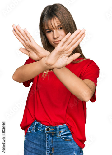 Teenager caucasian girl wearing casual red t shirt rejection expression crossing arms and palms doing negative sign, angry face