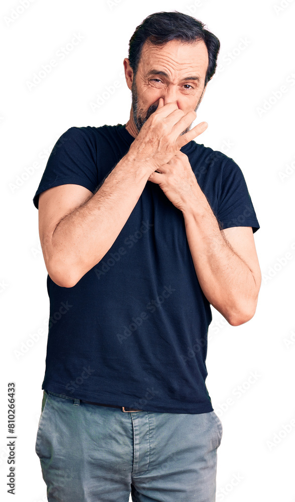 Middle age handsome man wearing casual t-shirt smelling something stinky and disgusting, intolerable smell, holding breath with fingers on nose. bad smell Middle age handsome man wearing casual t-shirt smelling something stinky and disgusting, intolerable smell, holding breath with fingers on nose. bad smell