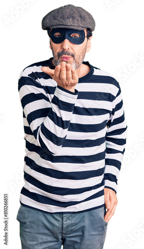 Middle age handsome man wearing burglar mask looking at the camera blowing a kiss with hand on air being lovely and sexy. love expression. © Krakenimages.com