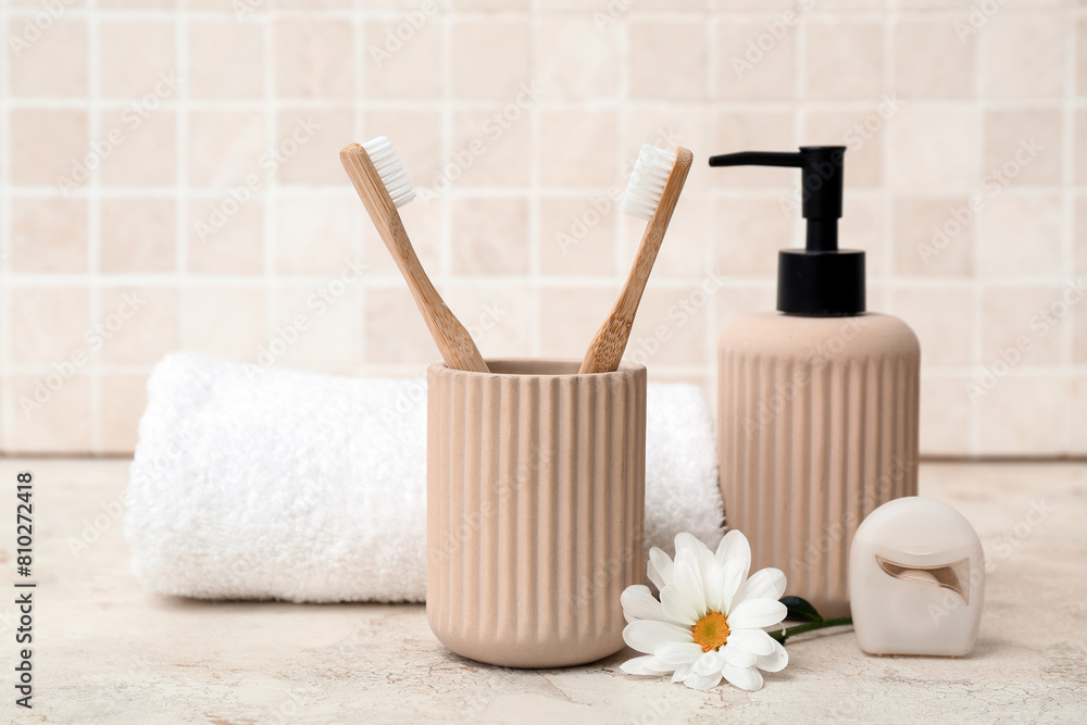Set of bath supplies on table against light tile background Set of bath supplies on table against light tile background