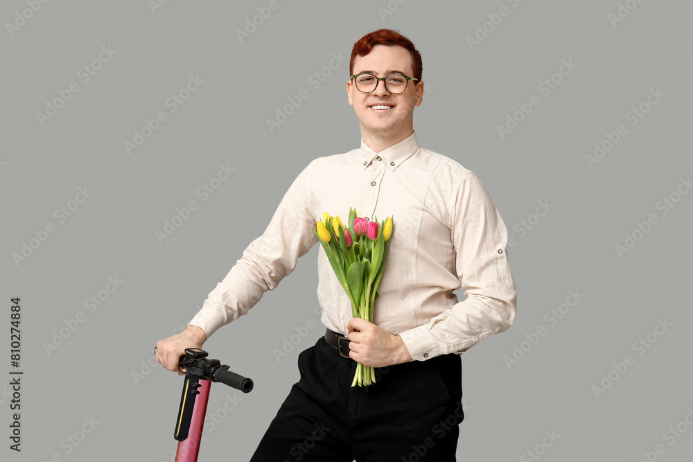 Young man with modern electric kick scooter and bouquet of beautiful tulips on grey background Young man with modern electric kick scooter and bouquet of beautiful tulips on grey background